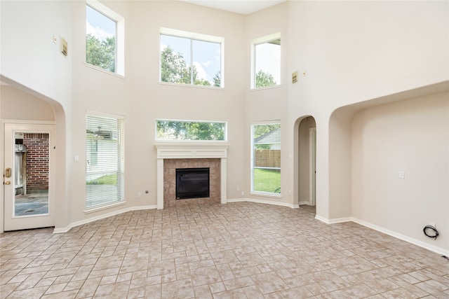 unfurnished living room with a tiled fireplace and a high ceiling