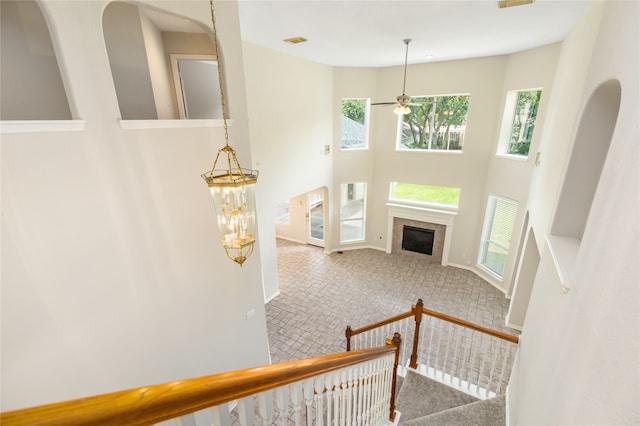 entryway with a healthy amount of sunlight, carpet flooring, ceiling fan with notable chandelier, and a tiled fireplace