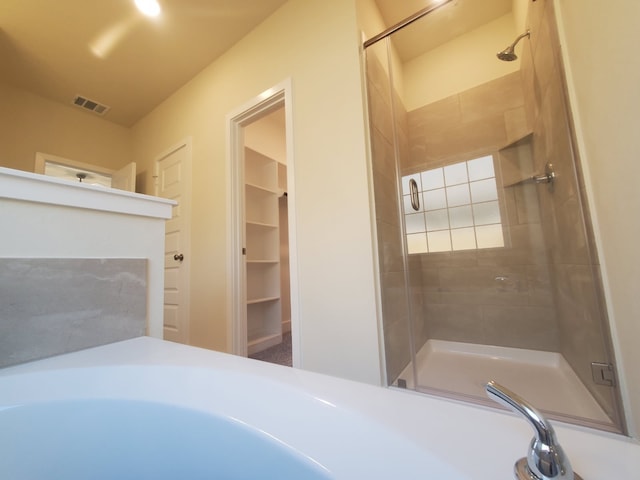 bathroom with a shower stall, a spacious closet, and visible vents