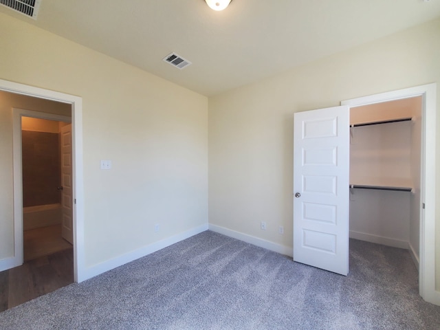 unfurnished bedroom featuring baseboards, a spacious closet, visible vents, and carpet flooring