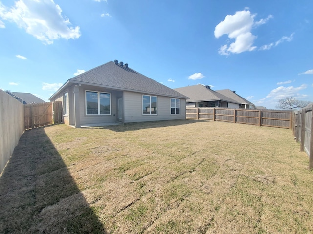 back of property featuring roof with shingles, a lawn, and a fenced backyard