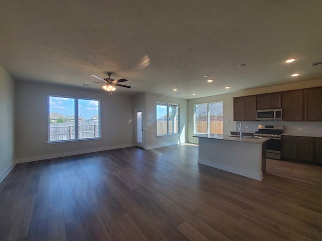 kitchen with a wealth of natural light, appliances with stainless steel finishes, dark wood-type flooring, open floor plan, and a sink