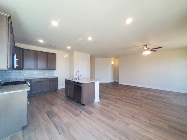 kitchen featuring tasteful backsplash, open floor plan, a sink, wood finished floors, and dishwasher