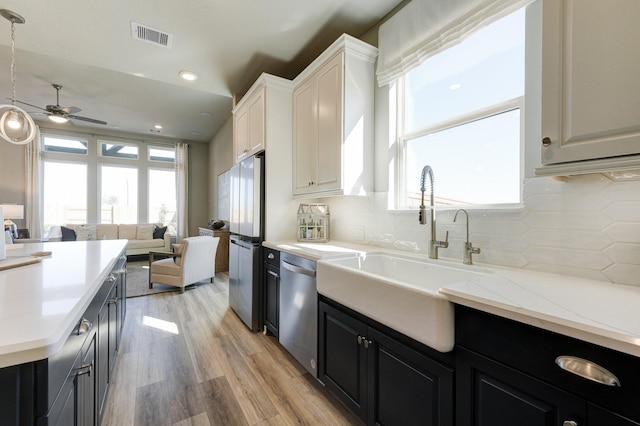kitchen with dark cabinets, backsplash, appliances with stainless steel finishes, open floor plan, and ceiling fan