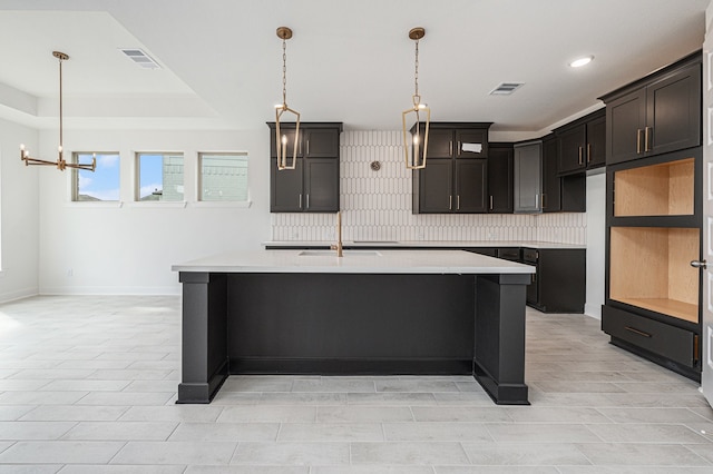 kitchen featuring dark brown cabinetry, a center island with sink, backsplash, and sink