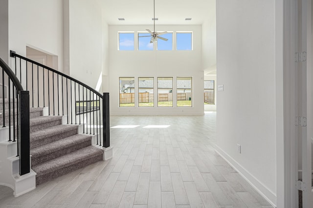 foyer entrance with light hardwood / wood-style flooring, a high ceiling, and ceiling fan