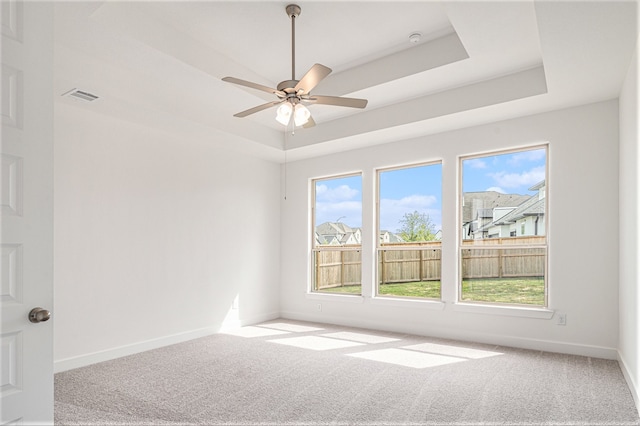 empty room featuring ceiling fan, a raised ceiling, and carpet floors