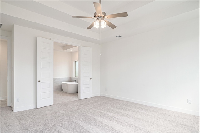 unfurnished bedroom featuring light carpet, connected bathroom, and ceiling fan