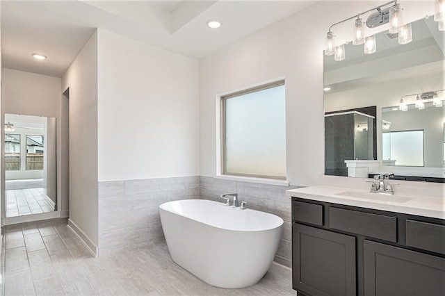 bathroom with plus walk in shower, tile walls, and vanity