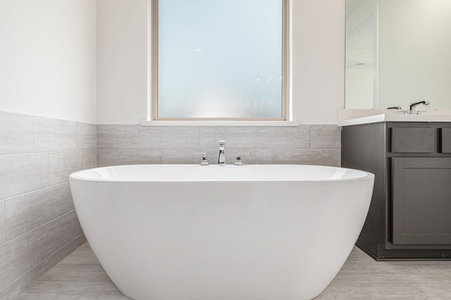 bathroom with a bathtub, tile walls, vanity, and tile patterned floors