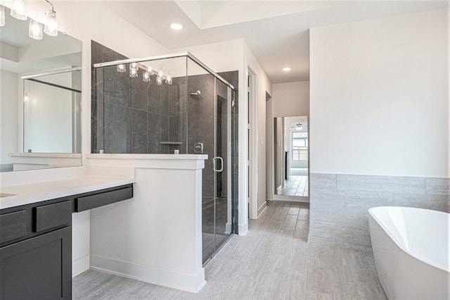 bathroom with wood-type flooring, vanity, and shower with separate bathtub