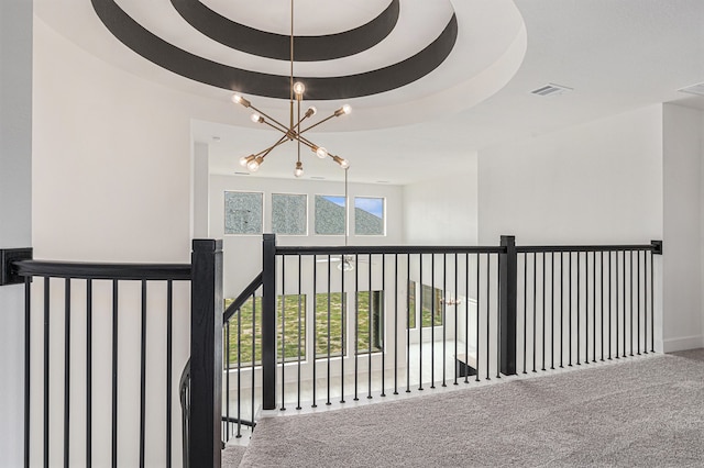 stairs with an inviting chandelier, a raised ceiling, and carpet