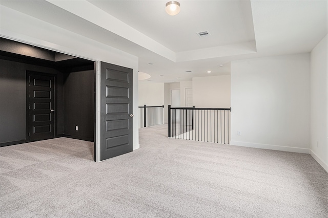 spare room featuring a tray ceiling and light colored carpet