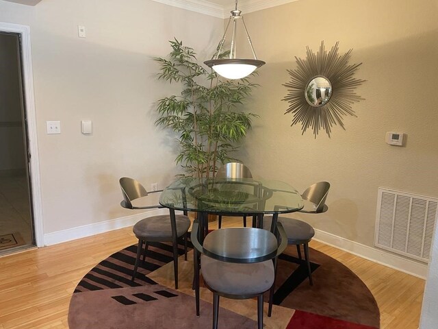 dining area featuring light wood-type flooring and crown molding