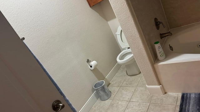 bathroom with tile patterned floors, toilet, and a tub