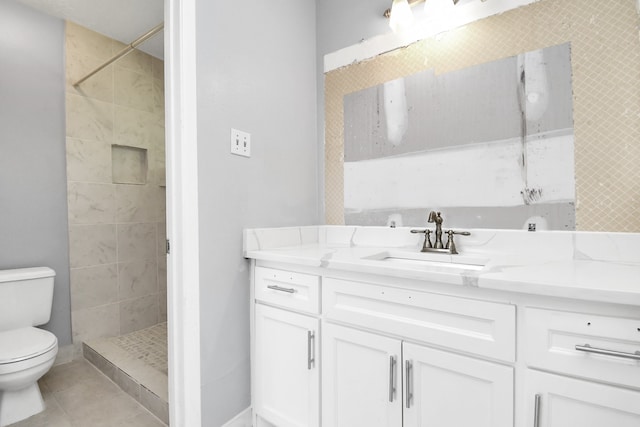 bathroom featuring tile patterned floors, toilet, vanity, and tiled shower