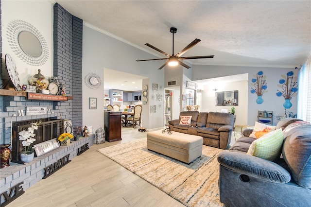 living room featuring a textured ceiling, a fireplace, light hardwood / wood-style flooring, ornamental molding, and ceiling fan