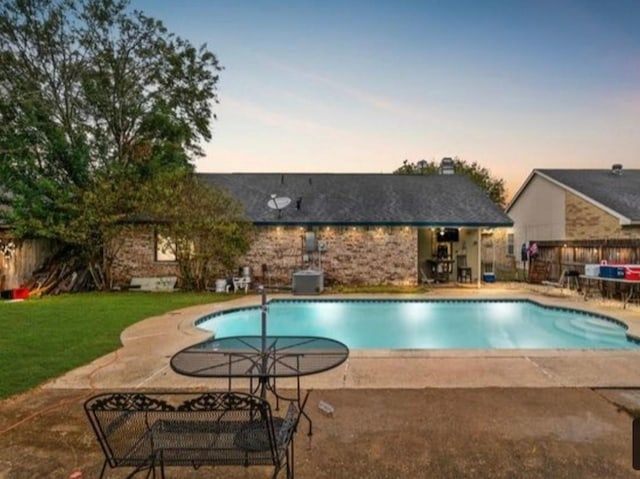 pool at dusk with a lawn and a patio