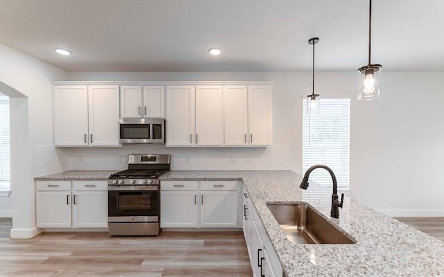 kitchen with pendant lighting, white cabinets, sink, and appliances with stainless steel finishes