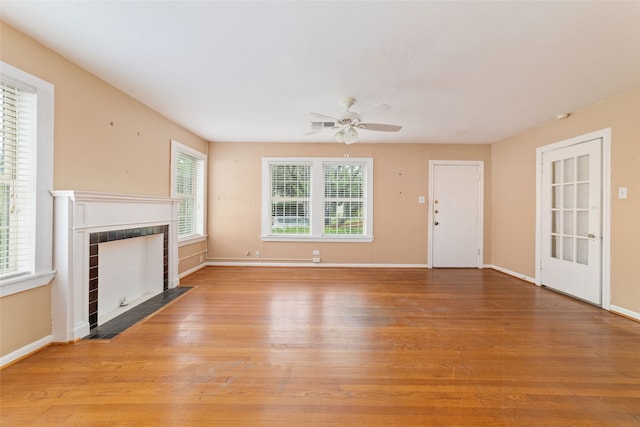 unfurnished living room featuring light wood-type flooring, a tile fireplace, and ceiling fan