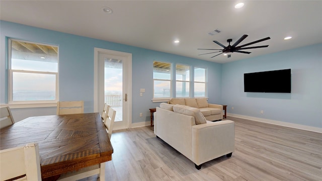 living room featuring light wood-type flooring, ceiling fan, and plenty of natural light