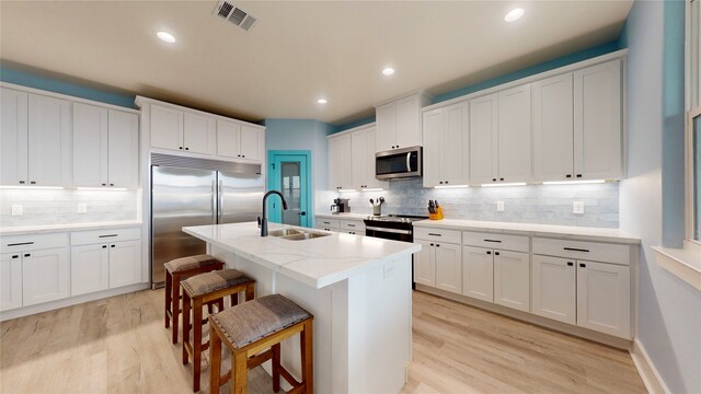 846 Alma, Crystal Beach, TX 77650 - kitchen with appliances with stainless steel finishes, a sink, backsplash, a breakfast bar, and light wood-style floors