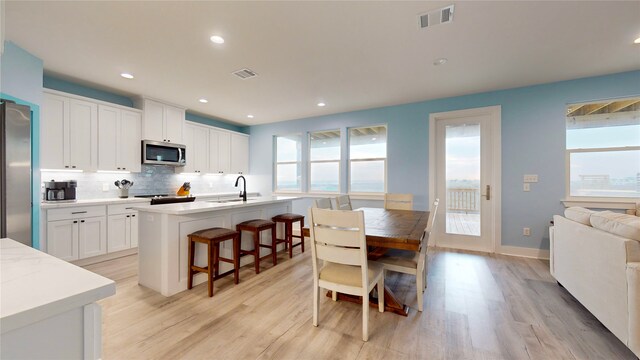 846 Alma, Crystal Beach, TX 77650 - kitchen featuring stainless steel appliances, light wood finished floors, backsplash, light countertops, and white cabinetry