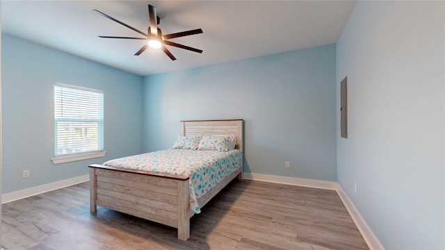 bedroom with ceiling fan, electric panel, and wood-type flooring