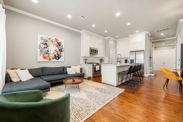 living room featuring ornamental molding, wood-type flooring, and sink