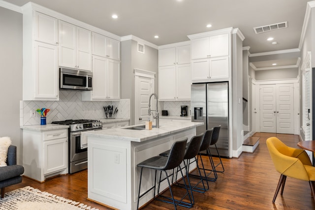 kitchen with a kitchen island with sink, stainless steel appliances, sink, and dark hardwood / wood-style flooring