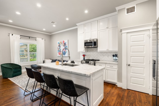 kitchen featuring dark hardwood / wood-style floors, sink, white cabinetry, a center island with sink, and appliances with stainless steel finishes