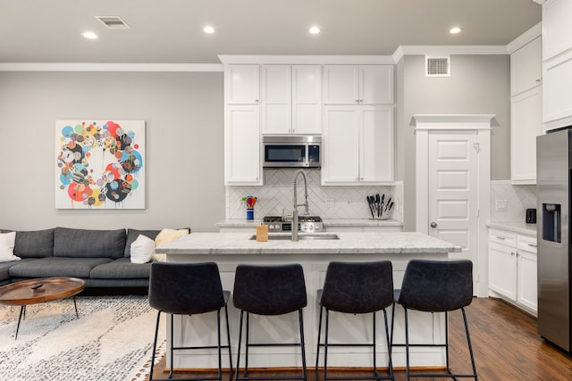 kitchen with a center island with sink, dark hardwood / wood-style flooring, stainless steel appliances, and white cabinets