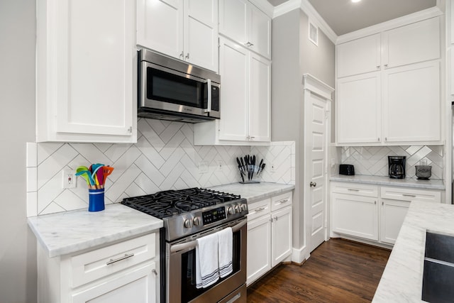 kitchen with appliances with stainless steel finishes, decorative backsplash, light stone countertops, and dark wood-type flooring