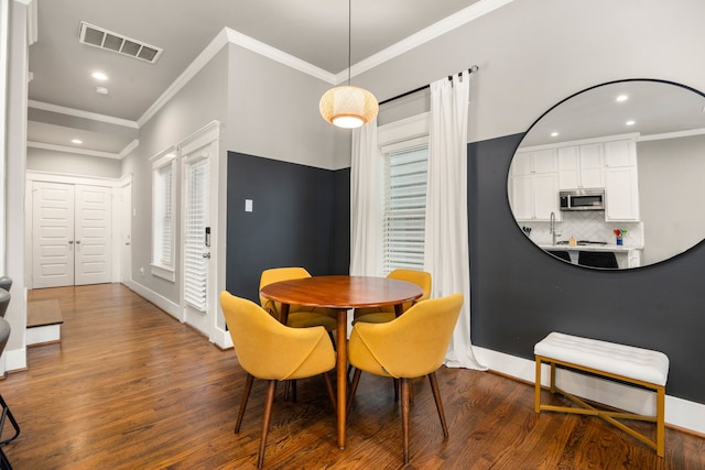 dining space with sink, crown molding, and dark hardwood / wood-style flooring