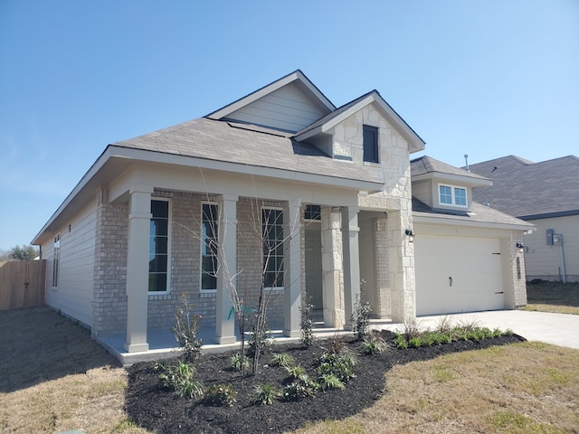 view of front of house with covered porch, a garage, brick siding, fence, and driveway