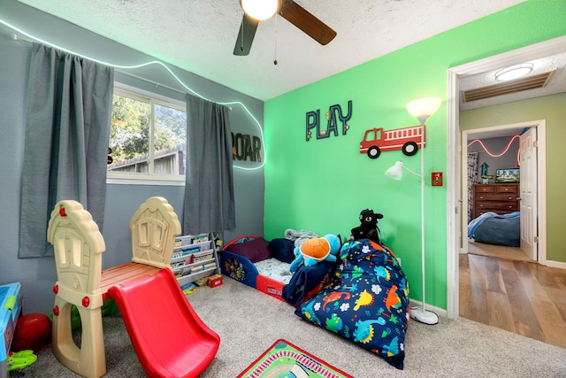 rec room with a textured ceiling, hardwood / wood-style flooring, and ceiling fan