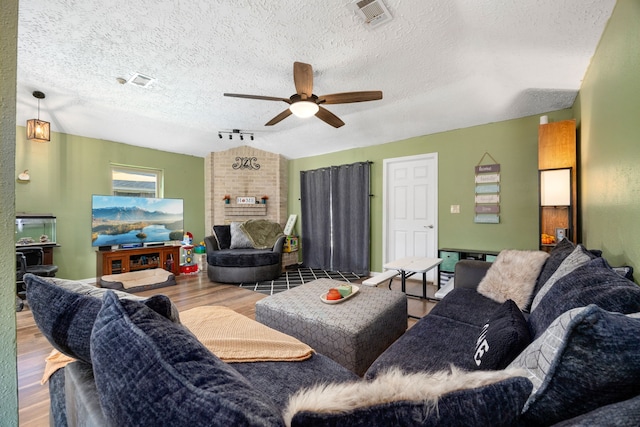 living room with a textured ceiling, vaulted ceiling, ceiling fan, and hardwood / wood-style flooring