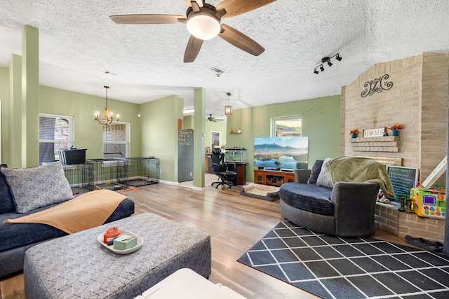 living room with a textured ceiling, ceiling fan with notable chandelier, hardwood / wood-style floors, and plenty of natural light