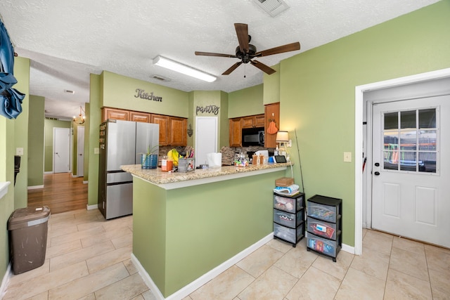 kitchen featuring ceiling fan, stainless steel fridge, kitchen peninsula, tasteful backsplash, and a textured ceiling