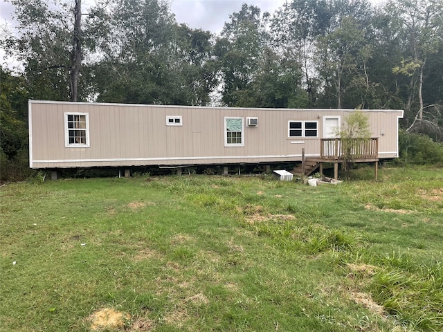 rear view of house with a deck, a yard, and a wall unit AC