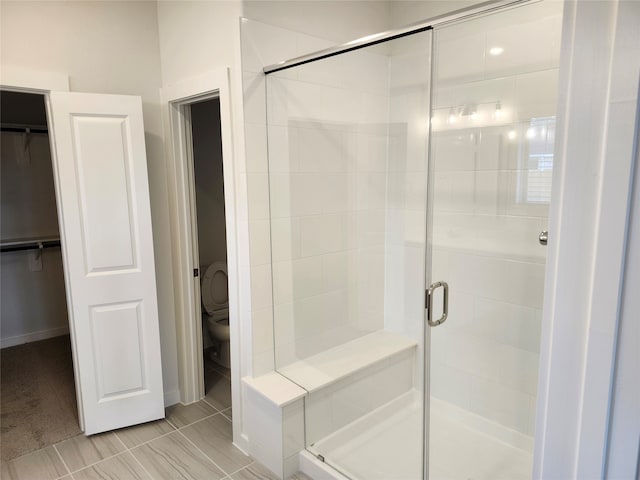 bathroom featuring a shower with door and toilet