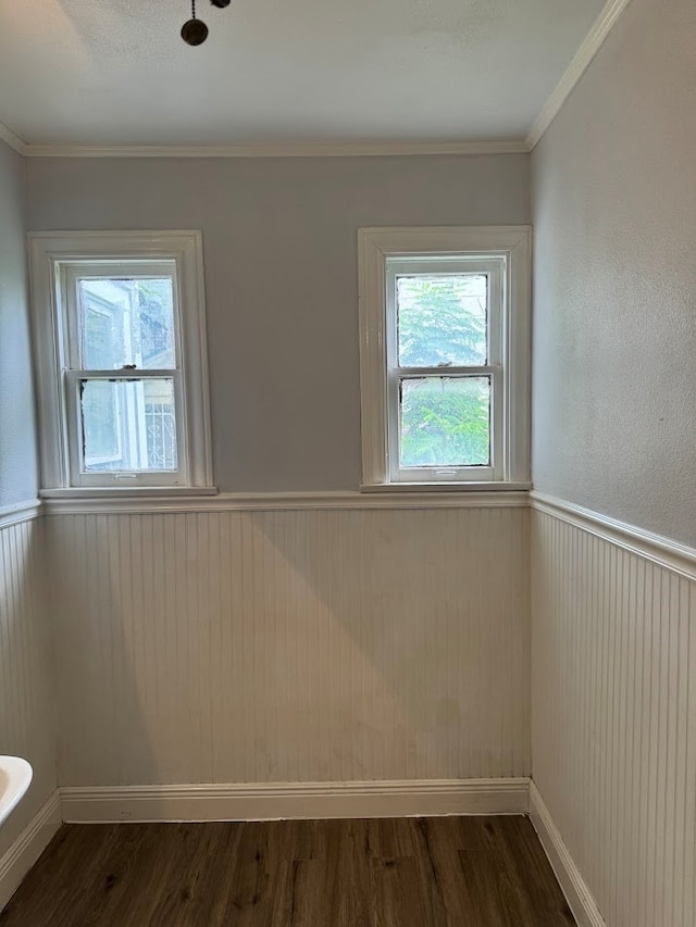 empty room featuring wood walls, dark wood-type flooring, and crown molding