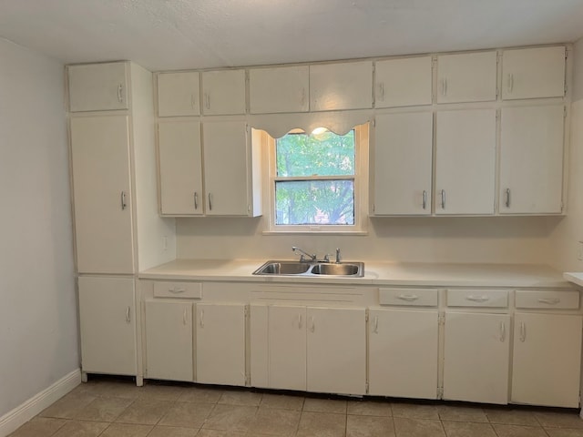 kitchen featuring white cabinets, light tile patterned flooring, and sink