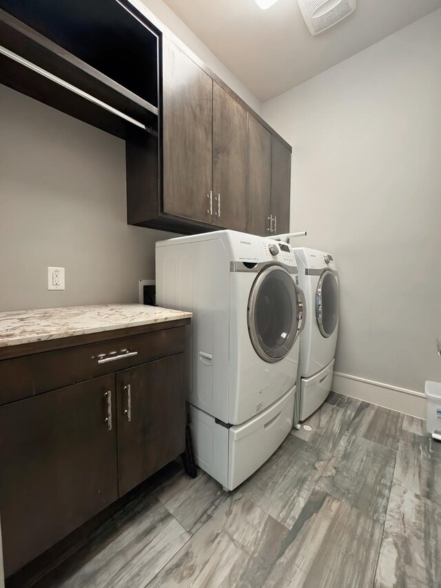 laundry area featuring separate washer and dryer, cabinets, and light wood-type flooring