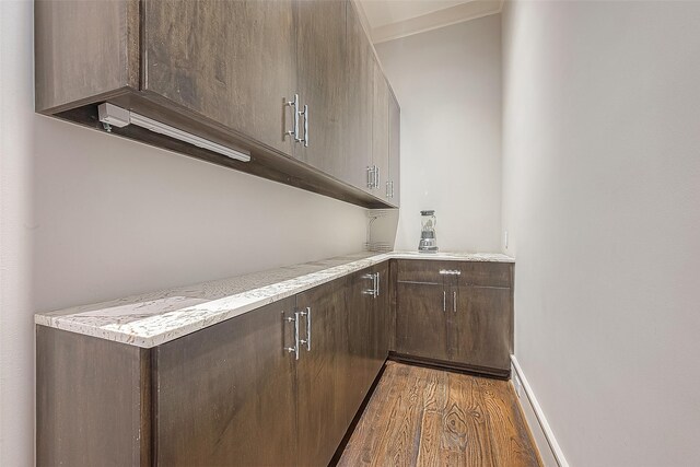 bar with dark brown cabinets and dark hardwood / wood-style floors