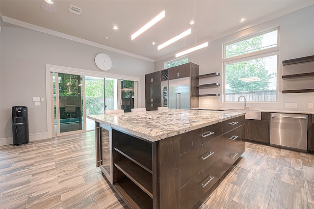 kitchen featuring appliances with stainless steel finishes, a healthy amount of sunlight, a kitchen island, and sink