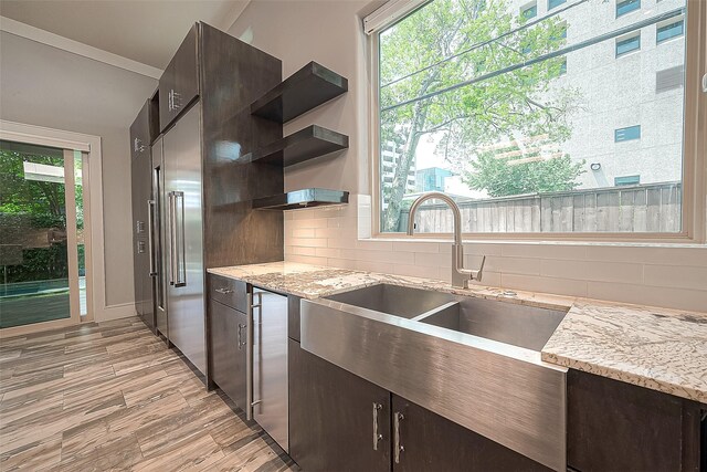 kitchen featuring a healthy amount of sunlight, backsplash, and dark brown cabinets