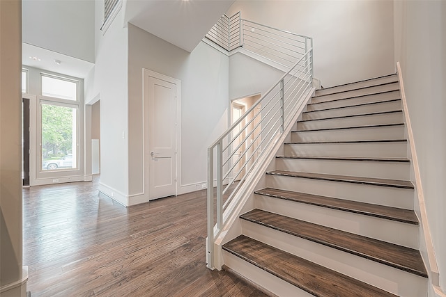 stairway with a towering ceiling and hardwood / wood-style floors