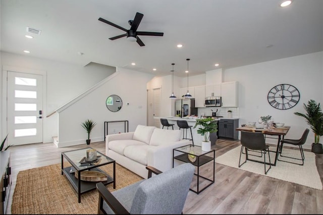 living room with ceiling fan and light hardwood / wood-style flooring