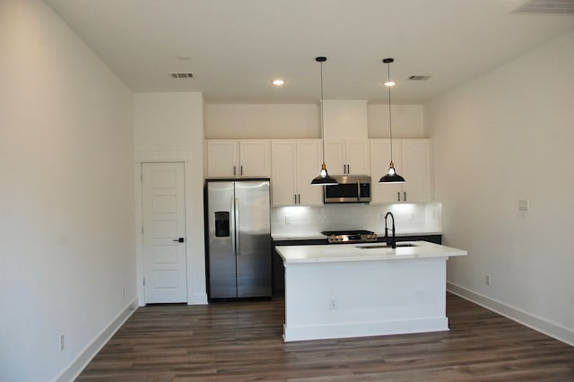 kitchen featuring appliances with stainless steel finishes, an island with sink, white cabinets, dark hardwood / wood-style flooring, and sink